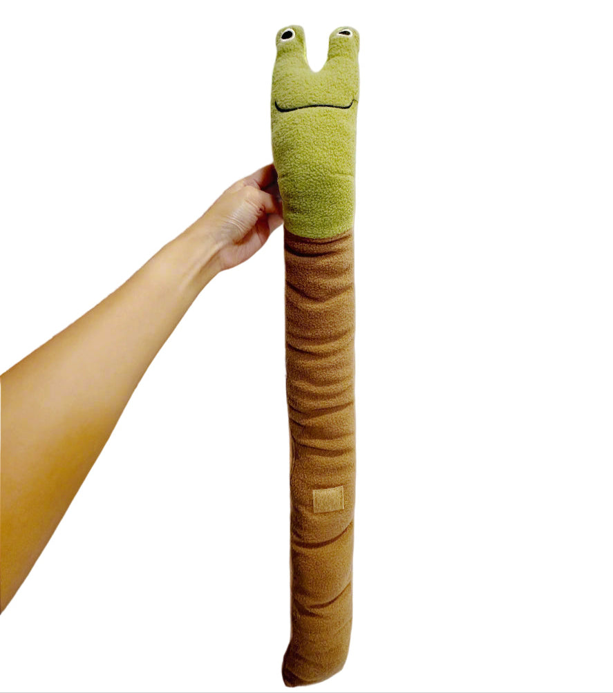 Green and brown plush toy shaped like a snake held by a hand against a white background